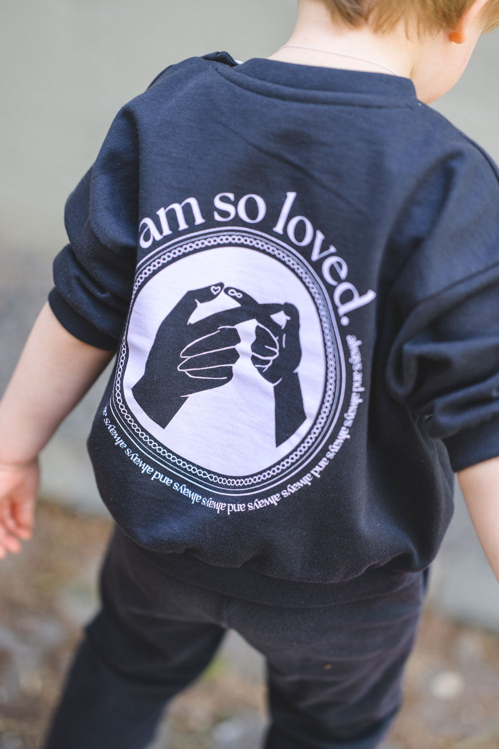 Kind trägt Sweatshirt in Anthrazit mit lavendelfarbenem Print