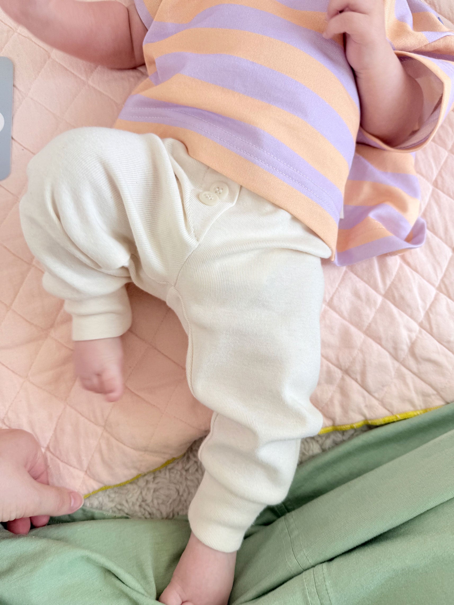 Baby trägt gemütliche Hosein hellem beige aus Biobaumwolle