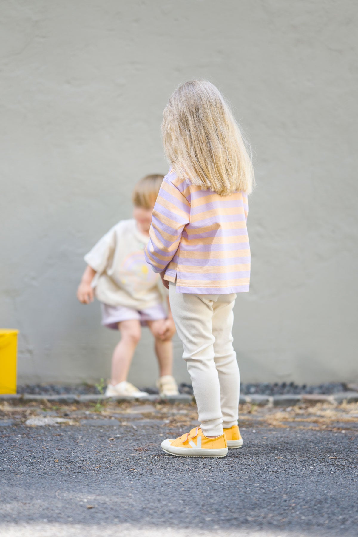 Kind trägt helle leggings mit weitem Longsleeve mit Streifenoptik