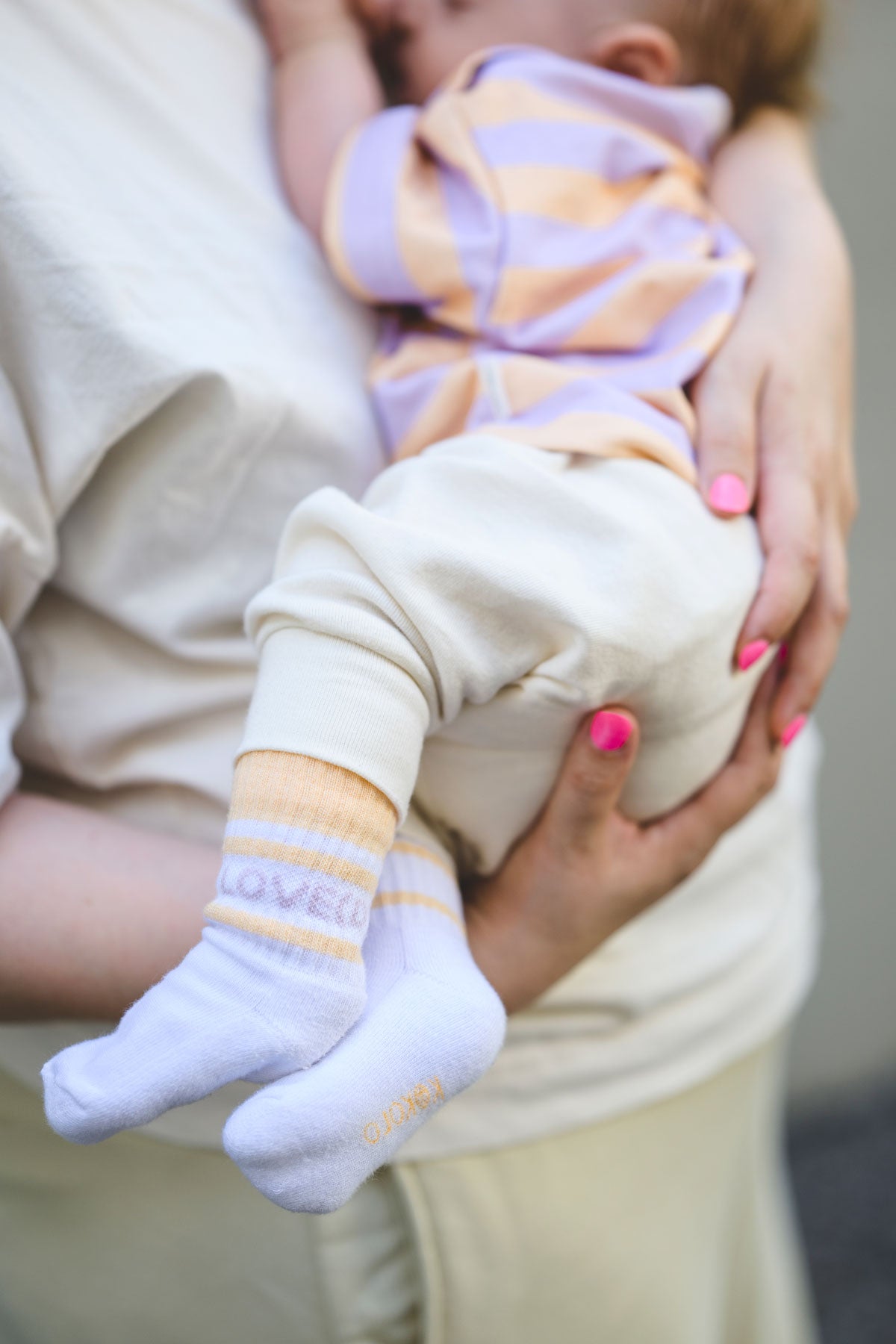 Baby trägt Tennissocken mit Aufschrift "loved"