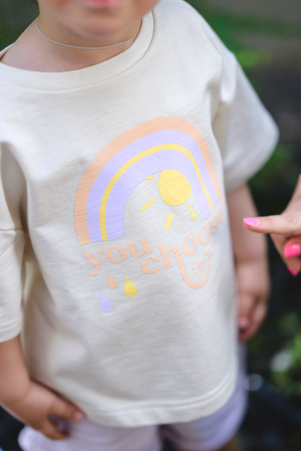 Kind trägt lockeres tshirt mit einem regenbogenprint